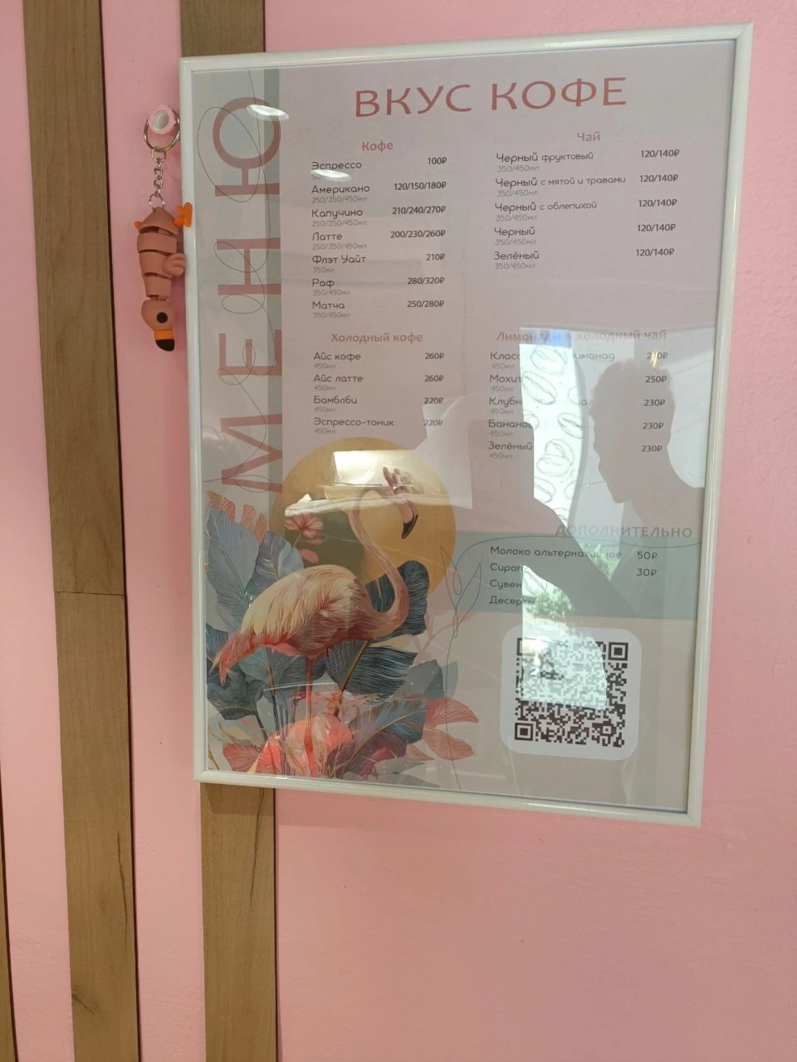 Напечатанное меню кофейни в рамке на розовой стене
